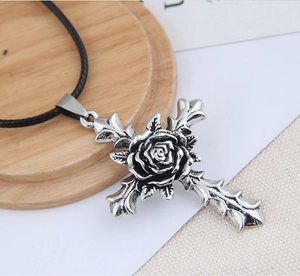 Detail of vintage silver cross necklace with embossed rose on a rustic wooden background