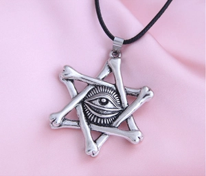 Detailed shot of vintage silver devil eye star pendant on pink satin background