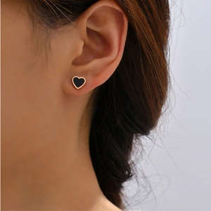 Minimalist heart-shaped stud earrings in rose gold and black finish shown on model