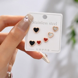 Close-up of heart-shaped titanium steel studs in black, red, and white shell finishes
