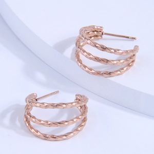 Elegant rose gold triple twisted hoop earrings on white geometric pedestal