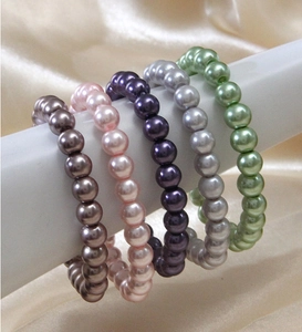 Detail of 0.8cm pearl bracelets in five colors displayed on a stand with silk background