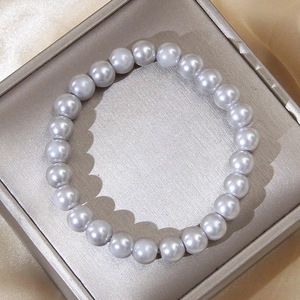 Detailed view of grey pearls bracelet with high luster on gold satin fabric background