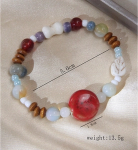 Détail d'un bracelet en perles de céramique colorées avec breloque feuille et perle rouge