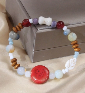 Bracelet ethnique avec disques en céramique rouge et perles de feuilles sur un écrin