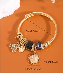 Detail of gold beaded bracelet featuring bear and sunflower charms with size measurements