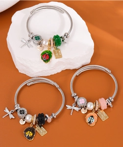 Détail de bracelets en fil perlé avec pendentifs libellule et breloques émaillées