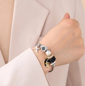 Gros plan du bracelet perlé avec breloques libellule, perle et trèfle sur chaîne serpent