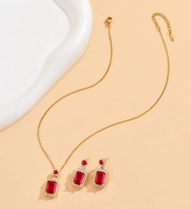 Detailed close-up of golden jewelry set featuring red emerald-cut gems and diamonds