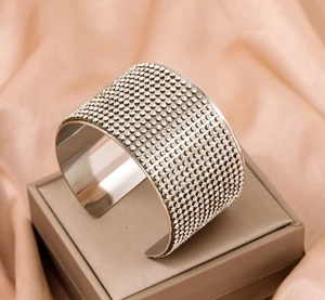 Macro shot of silver-tone wide cuff bracelet encrusted with rows of sparkling white rhinestones