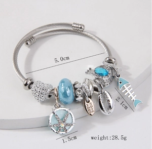 Detail of silver charm bracelet with blue glass beads, shells and starfish pendants