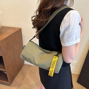Sac bandoulière cylindrique en nylon vert olive avec étiquette jaune et bandoulière