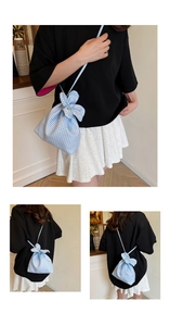 Detail of blue gingham drawstring bucket bag with bunny ear knots and slim strap