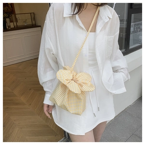 Detailed view of yellow gingham bucket bag featuring a large decorative bow and strap