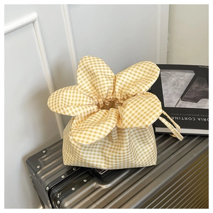 Detail of yellow gingham canvas bucket bag with floral drawstring closure on luggage