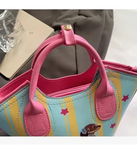 Detail of pink leather handles and cartoon dog print on a striped bucket handbag