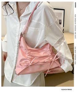 Detail der rosa gefalteten Tasche mit Schleifen, glänzendem Finish und Silberkette