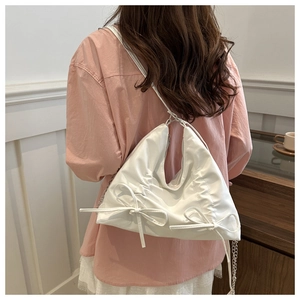 Detailansicht der weißen Cloud-Tasche mit Schleifen und silberner Kette am Model