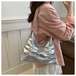 Detailaufnahme der silbernen Falten-Tote-Bag mit Metallic-Finish und Schleifen-Deko