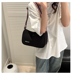 Detail of black crescent canvas crossbody bag with striped wide strap and Fanyissa logo