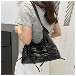 Detailansicht der schwarzen Rafftasche mit Schleifen und silbernem Kettenriemen