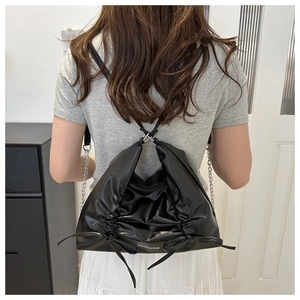 Detail eines schwarzen Rucksacks aus PU-Leder mit Falten, Schleifen und Metallketten