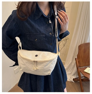 Detail view of cream crescent crossbody bag showing nylon fabric texture on a model