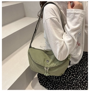 Détail du sac croissant en nylon vert avocat porté à l'épaule par le mannequin