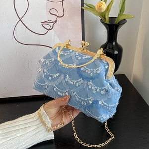 Light blue mesh crossbody bag with wave sequins and gold frame shown in hand