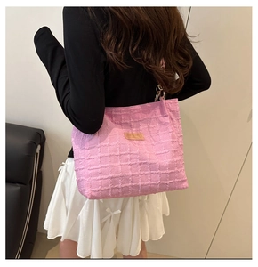 Pink checkered tote bag with textured fabric and brown leather patch worn on shoulder