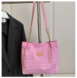 Detail of pink tweed tote bag showing logo leather patch and gold chain strap