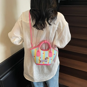 Pink dachshund bucket bag with striped pattern and stars shown on a model on stairs