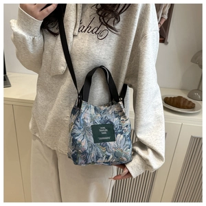 Detail view of a floral bucket bag showing vintage jacquard texture and black strap handle
