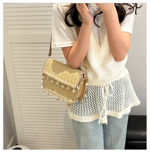 Close-up of woven straw bag with white lace trim and decorative shell charms detail