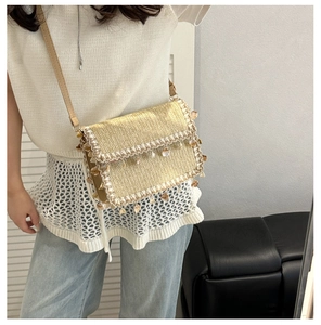 Detailed close-up of woven straw crossbody bag with shell tassels and lace trim