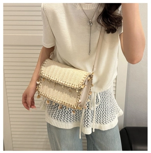 Detail of woven straw crossbody bag with seashell charms and white leather strap