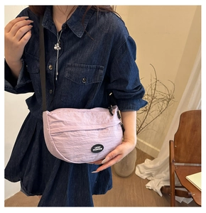 Detail of lavender nylon crescent bag featuring pleated texture and Lucky Fashion logo