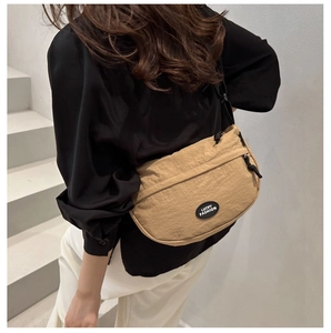 Detail showing the Lucky Fashion logo and khaki nylon fabric on the crescent crossbody bag