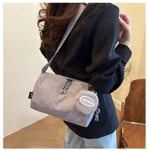 Detail van lichtpaarse geplooide hobo-tas met bijpassende kleine ronde pouch-accessoire