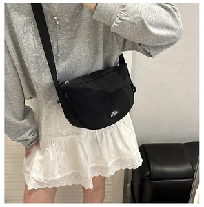 Close-up of black nylon crescent fanny pack with Lucky Fashion logo on a casual model