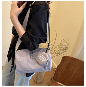 Detail van lila crossbodytas met een brede band en een klein rond accessoire portemonnee