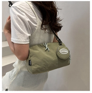 Saliegroene nylon hobotas met kleine ronde etui op model, casual zijwaanzicht