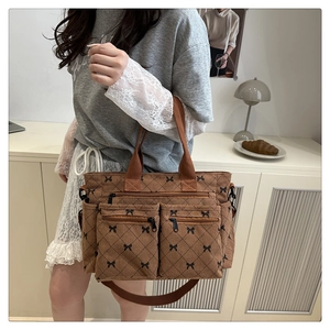 Brown corduroy tote bag with black bow lattice pattern and multiple zipper pockets