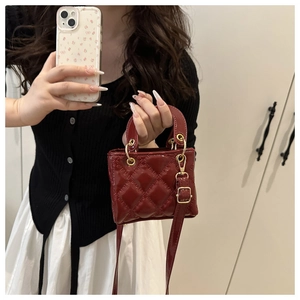 Detail of a bright red mini quilted bag with gold hardware and a circular handle