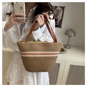 Detailaufnahme der handgefertigten Strohtasche mit buntem Wellenmuster und braunem Kunstledergriff