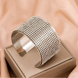 Elegant wide silver-tone open cuff bracelet with sparkling pavé crystals on a jewelry box