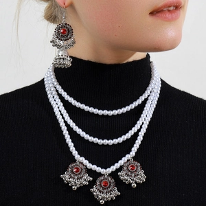 Three-layer pearl necklace and matching Jhumka earrings set with red gemstone accents
