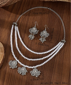 Detail view of vintage multilayer pearl necklace and matching bell earrings on wood base