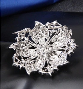 Macro view of the silver flower brooch back showing the metal pin fastener
