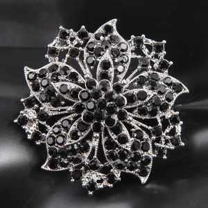 Detailed close-up of a silver flower brooch with pave-set black rhinestones
